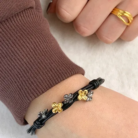 sort armband i läder med blommaberlock i förgyllt och rhodinerat silver